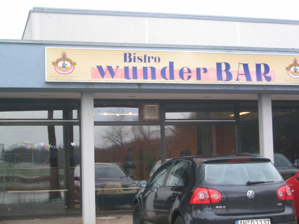 Bistro WunderBAR Fassade mit geparkten Autos. "Bistro WunderBAR" Schriftzug.
