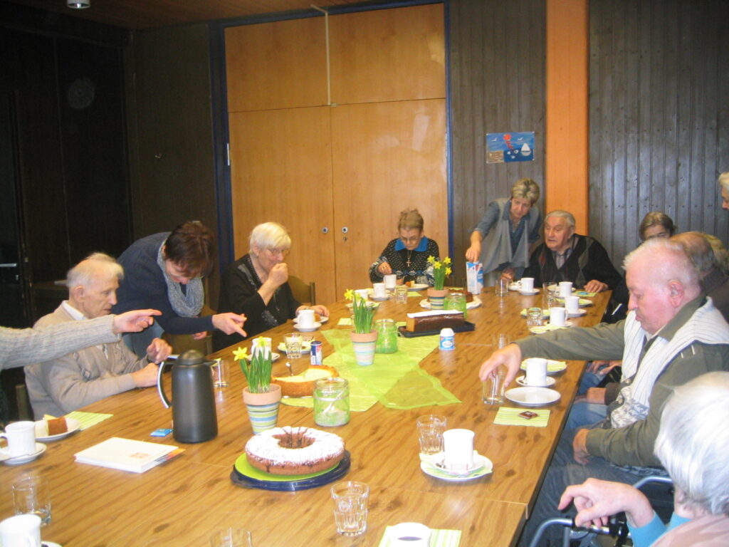 Betreuungsgruppe am Tisch: Senioren genießen Kaffee und Kuchen im neuen Zuhause.