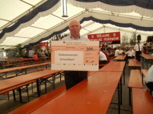 Man holding a large novelty check from Vereinigte Sparkassen for 300 EUR to Diakonieverein Schnelldorf.