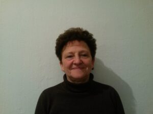 Portrait of a woman with short curly hair wearing a black turtleneck.