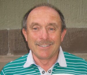 Portrait of a smiling man with a mustache wearing a striped shirt.