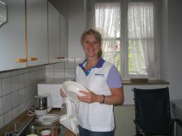 Frau wäscht Geschirr in der Küche. Sauberkeit ist uns wichtig.